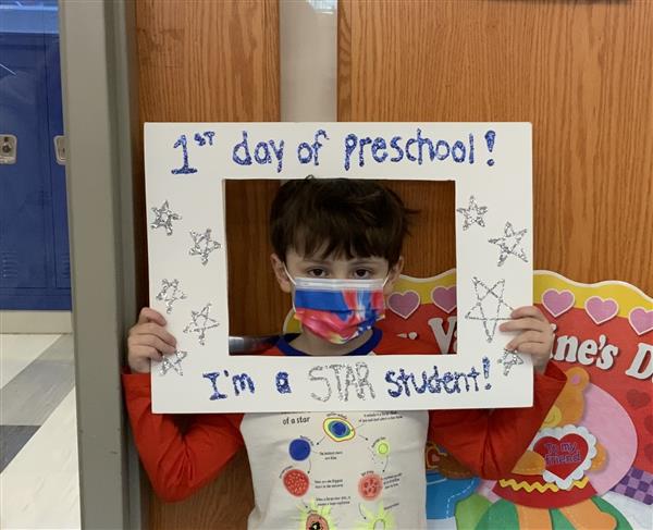 This picture is of LM on his first day of HP Preschool holding a first day sign.