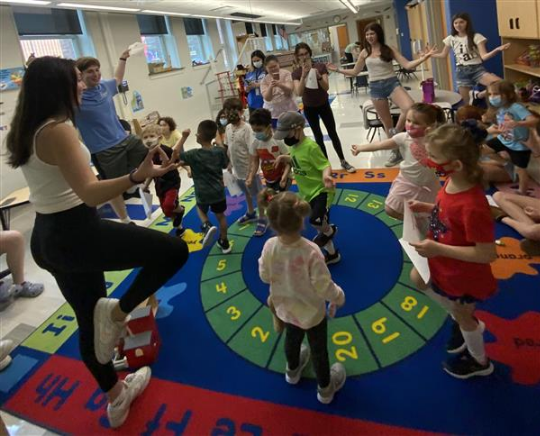 Children doing yoga poses on rug.