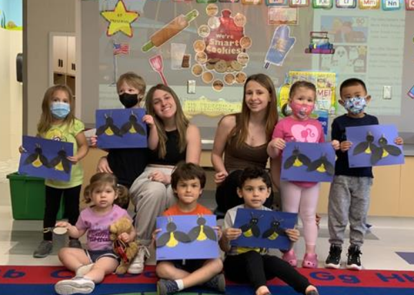 Children hold Fireflies art project at circle time.