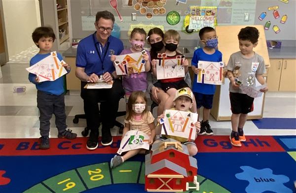 Dr. Law poses with the children and their farm art projects.